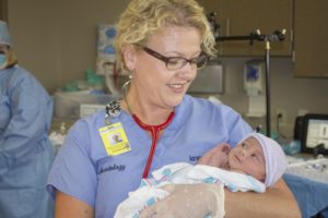 Nurse holding infant in hospital room