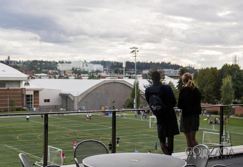 College students standing on balcony overlooking sports field