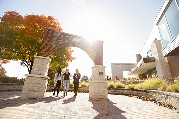 College students standing under arch at college campus