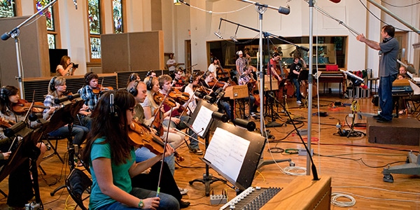 Orchestra students and conductor indoors