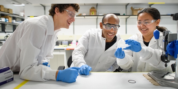 Students wearing lab coats and looking at a sample