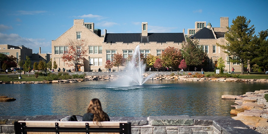 Outdoor view of college campus and student sitting on bench