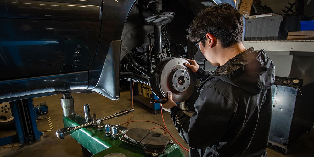 College student working on a car in garage