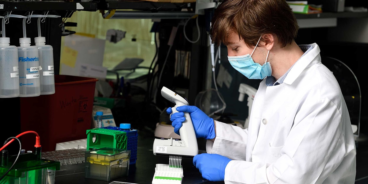 Student working in a lab wearing white lab coat