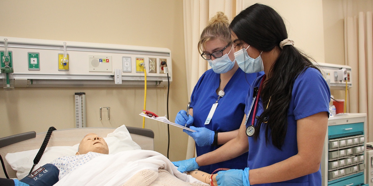 Nursing students working with dummy patient