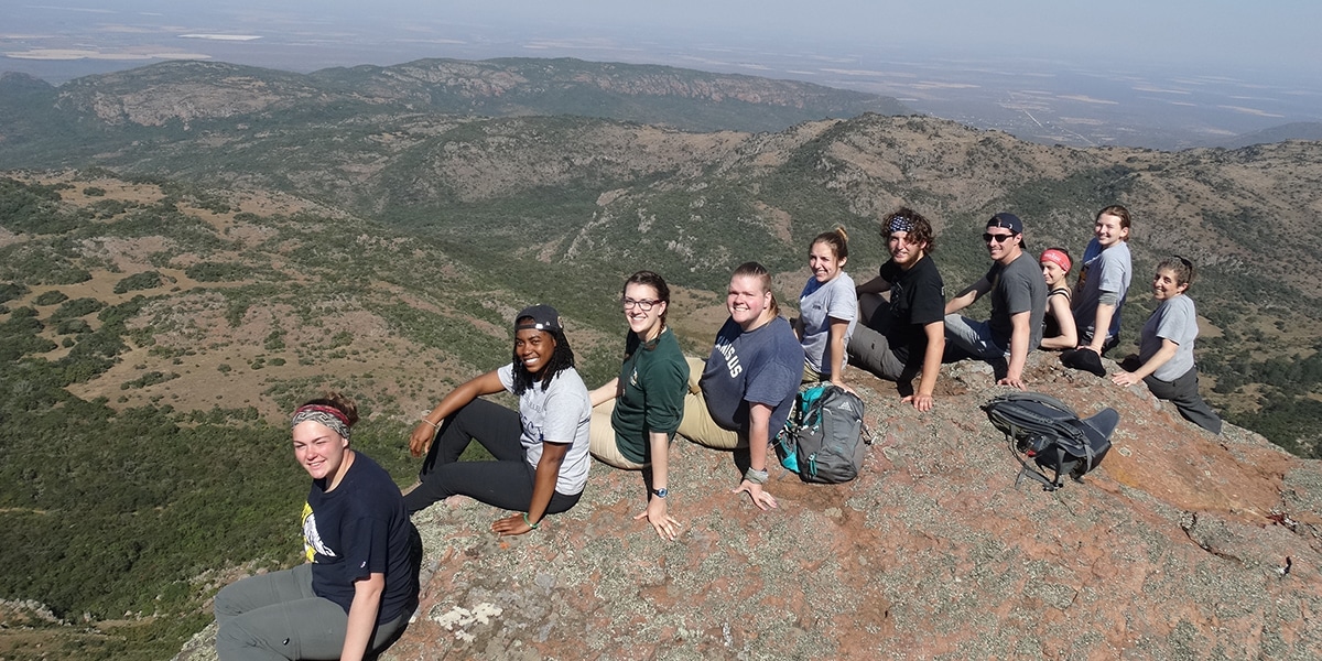 Students sitting on edge of cliff