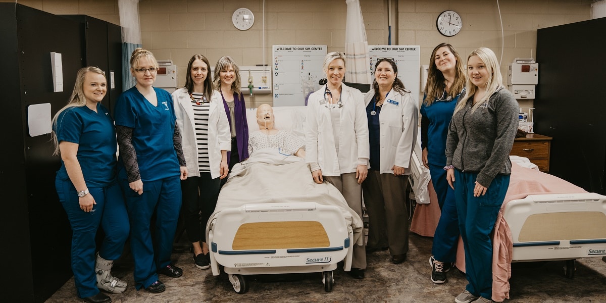 College students posing near hosital bed with dummy