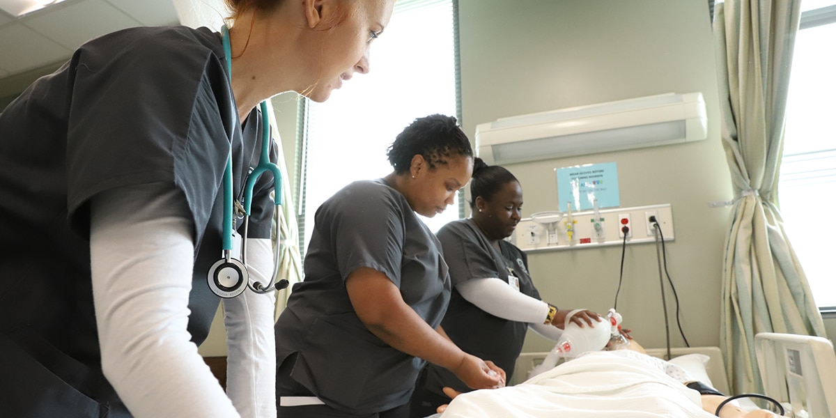 Nursing students working with dummy patient