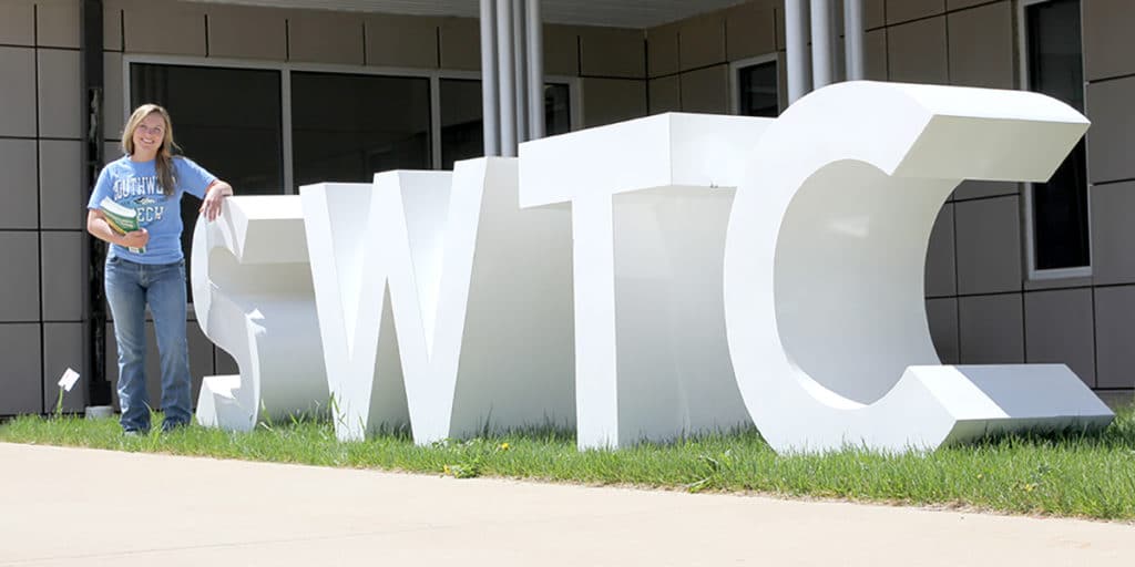 Student standing next to white SWTC sign outdoors