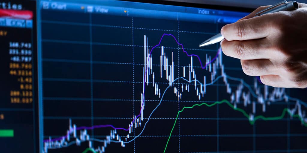 Hand holding a pen and pointing to screen with chart