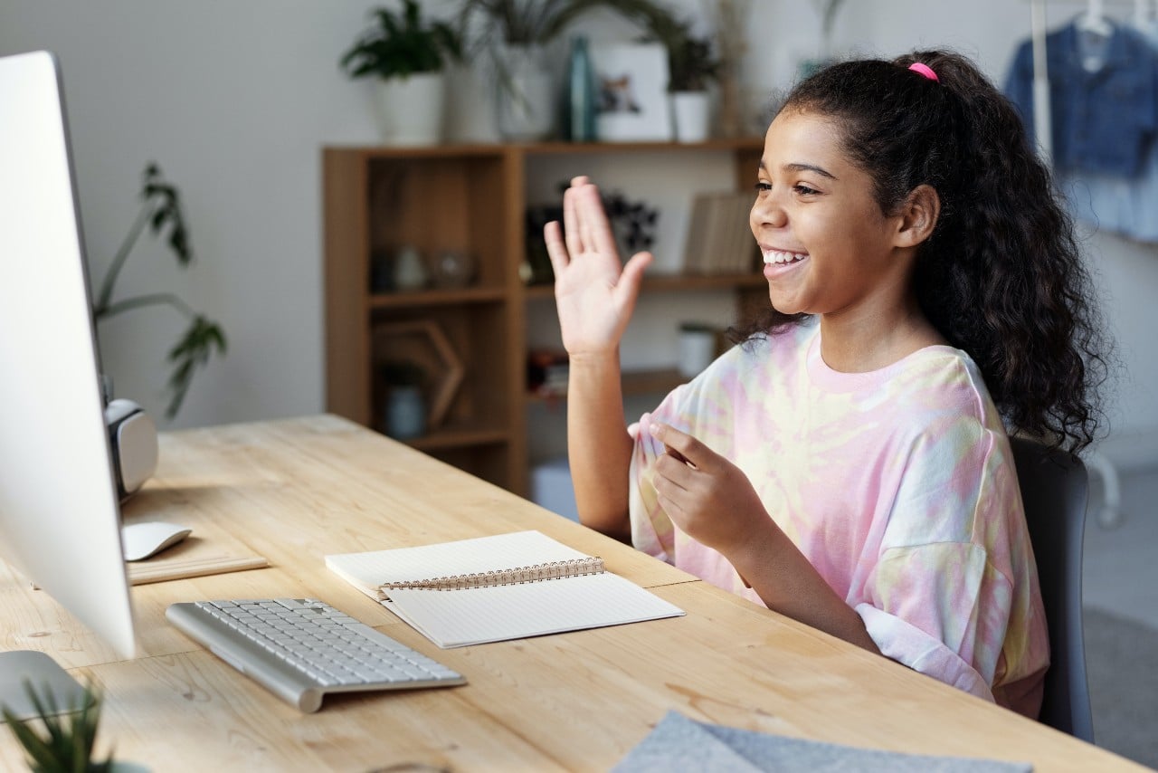 young girl student sitting in of computer waving